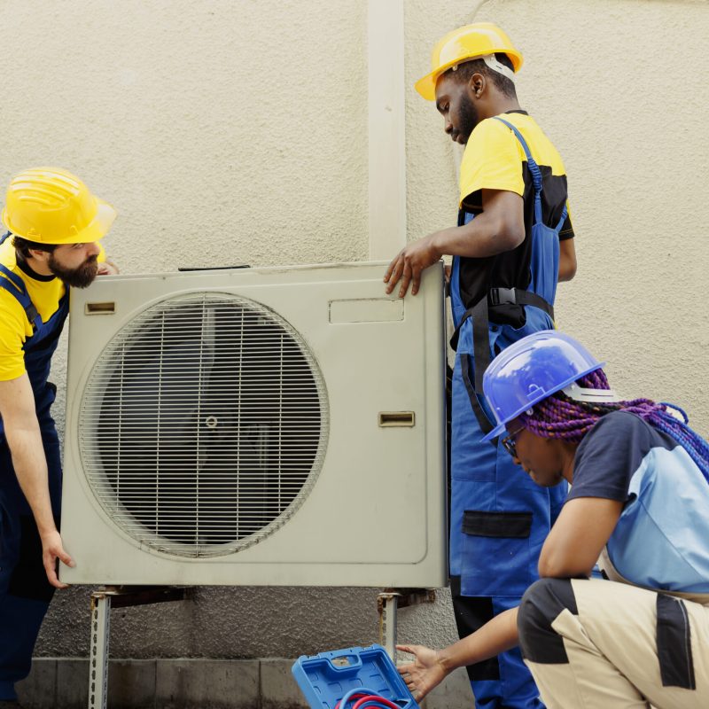 Knowleadgeable engineering team installing new outdoor air conditioner for home owner after replacing old condenser. Efficient technicians tasked with optimizing new HVAC system performance